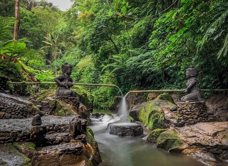 A serene waterfall in a lush forest with stone statues of deities. 2