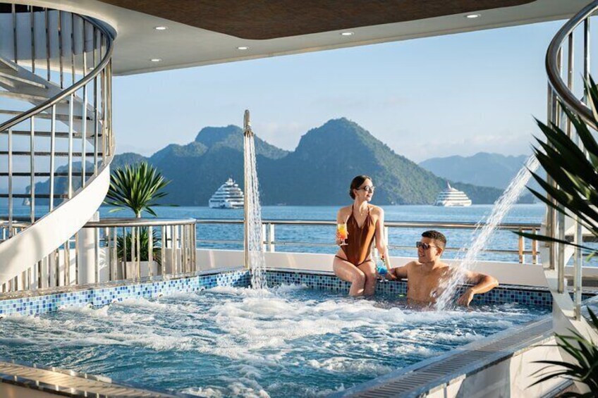 Un couple se détend dans un jacuzzi à bord d’un navire de croisière, avec vue sur la mer et les montagnes. 1
