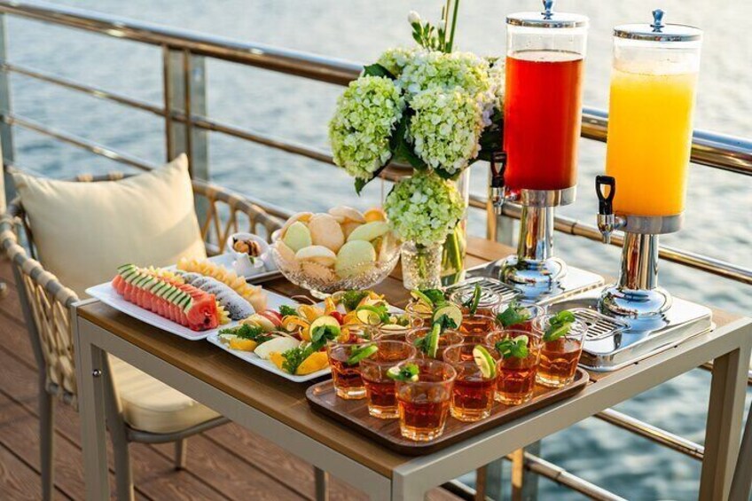 Une table dressée avec de la nourriture, des boissons et un arrangement floral sur le pont d’un bateau. 3
