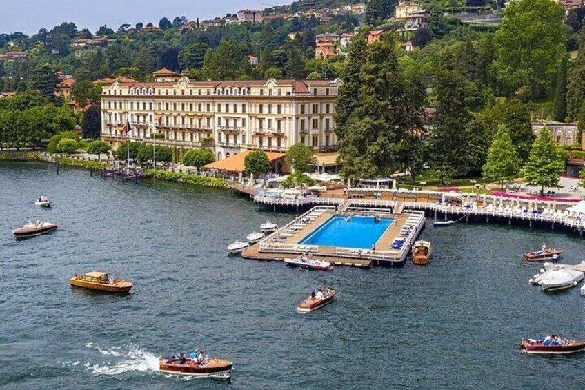 Ein See mit Booten, ein Schwimmbad und ein großes Gebäude mit einem Balkon. 5