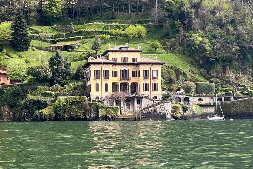A large yellow building with multiple windows, situated on a hillside by a body of water. 4