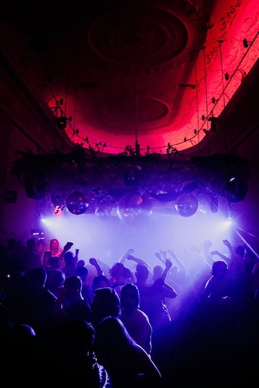 A crowd at a concert with a stage and disco balls. 5