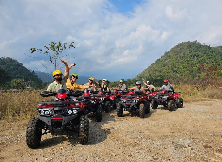 A group of people on ATVs on a dirt road with hills in the background. 1