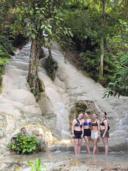 A group of people standing in a natural water feature surrounded by lush greenery. 5