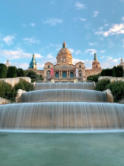 A grand building with domes and a large waterfall in front. 5