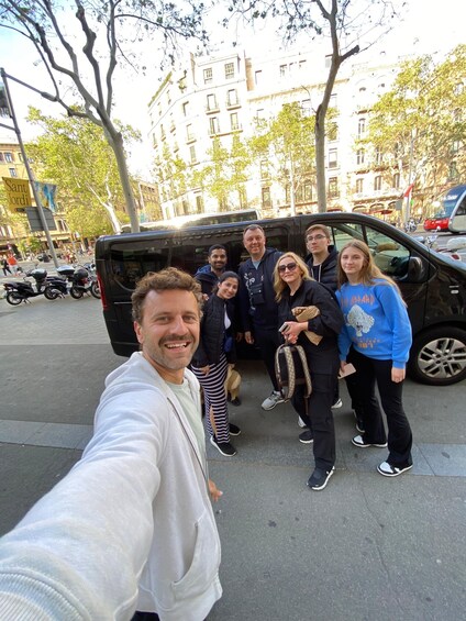 A group of people standing on a city street with buildings and parked cars in the background. 1
