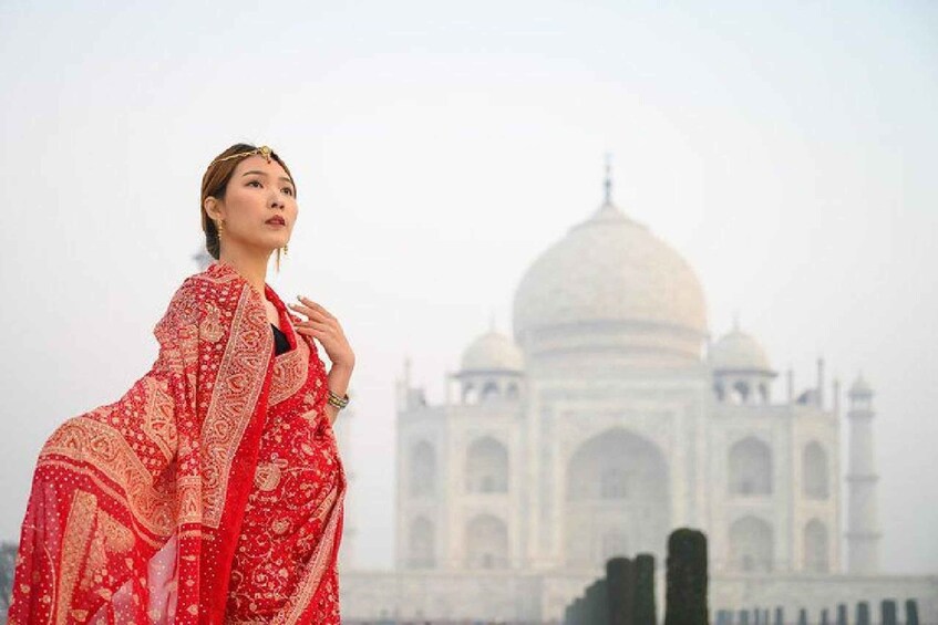 En person i traditionell dräkt med Taj Mahal i bakgrunden. 1