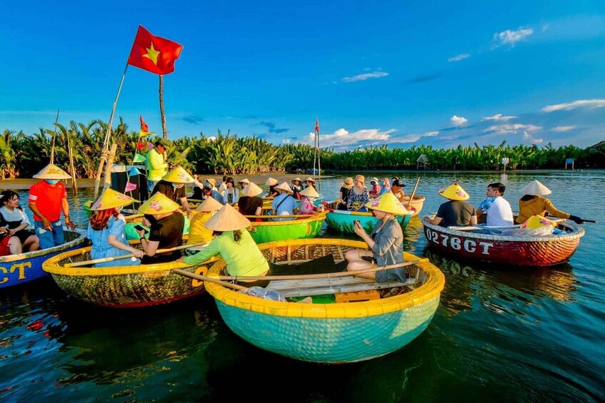A group of people in colorful boats on a calm body of water, with a flag flying above one boat. 5