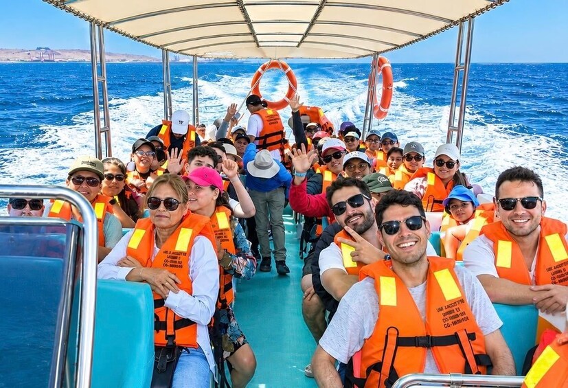 A group of people on a boat wearing life jackets, with lifebuoys and a clear view of the ocean. 1
