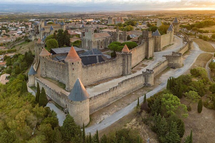 Un castillo medieval rodeado por una muralla fortificada, con un pueblo al fondo. 1