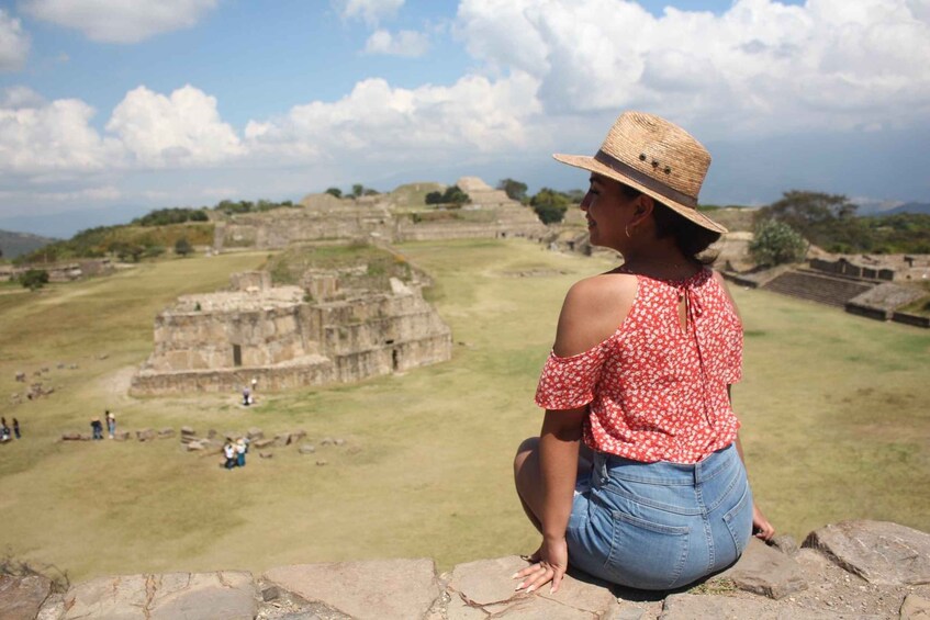A person sitting on a stone ledge overlooking ancient ruins. 1