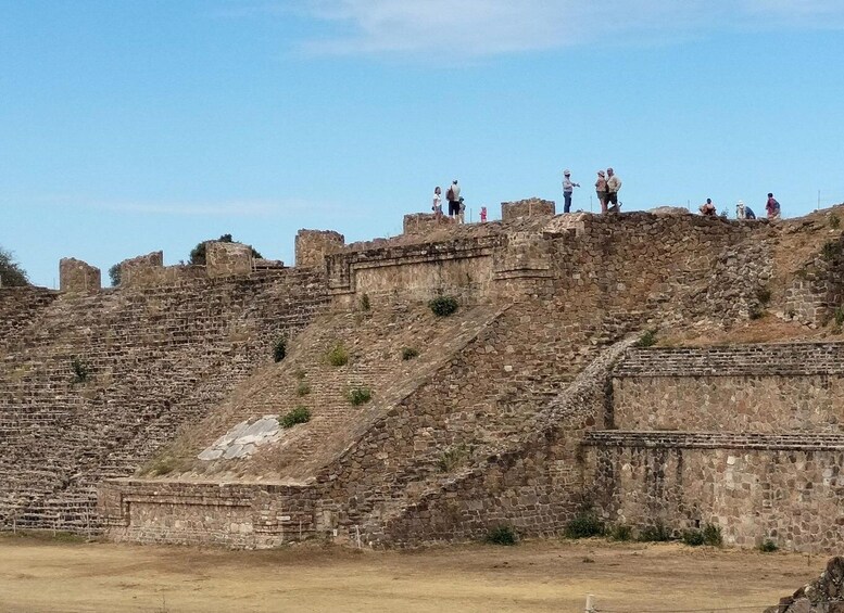 An ancient stone fortress with people standing on the walls. 5