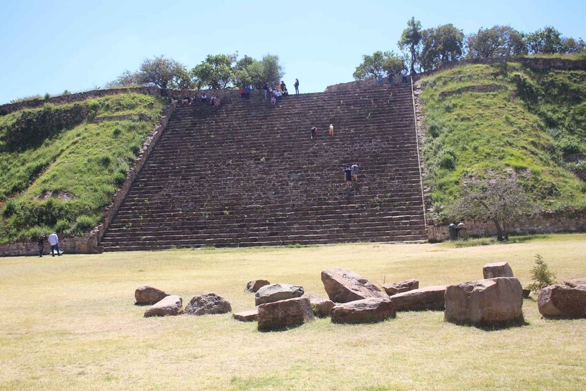 A large stepped structure with people at the top and large rocks in the foreground. 2