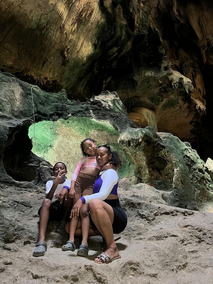 Three people sitting on a rocky surface with cave formations in the background. 2