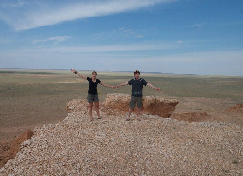 Two people standing on rocky terrain with a vast landscape in the background. 5