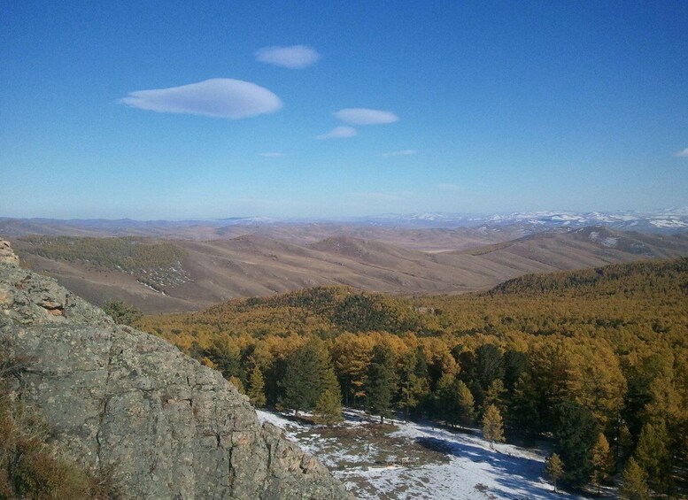 A mountainous landscape with autumn-colored trees and a snow-covered valley. 4