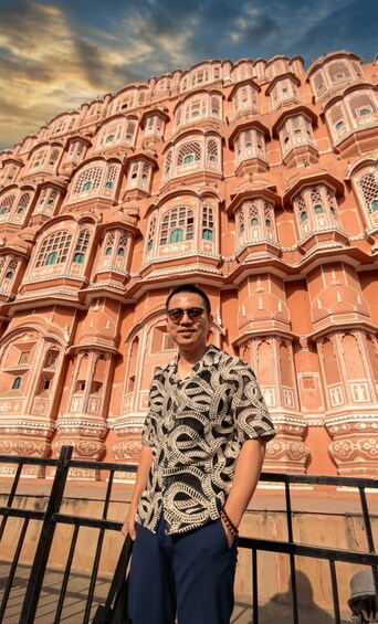 A person standing in front of a large, ornate building with intricate architectural details. 5