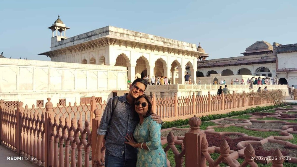 A couple posing in front of a historic building with arches and a domed structure. 5
