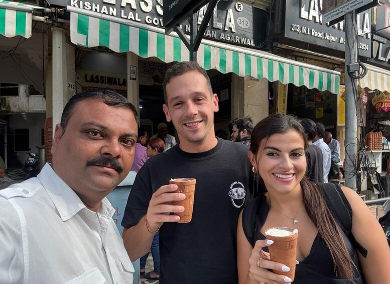 Three people posing in front of a street with shops. 5