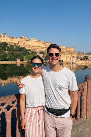 Two people standing in front of a historic fort with a reflection in the water. 2