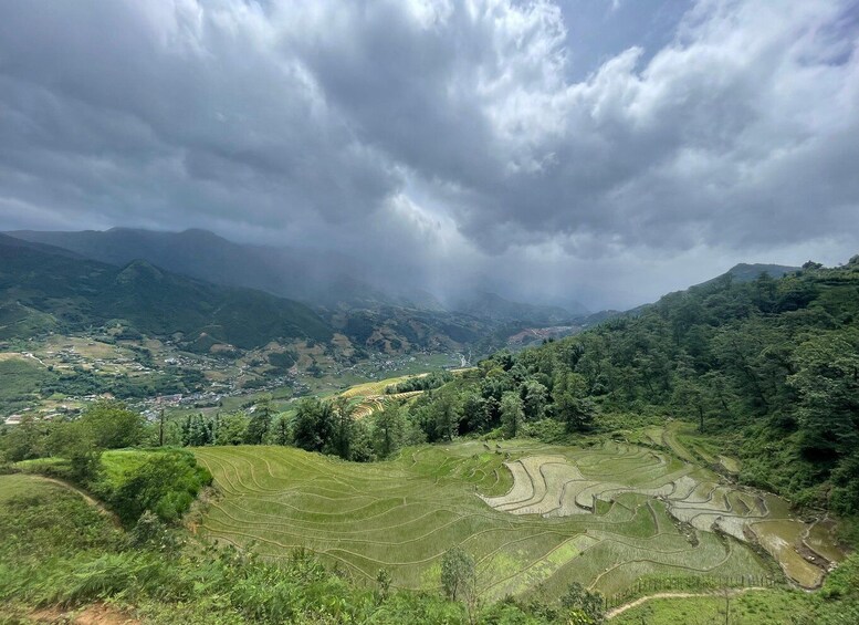 Terraced rice fields, a valley, and a mountain range under a cloudy sky. 1