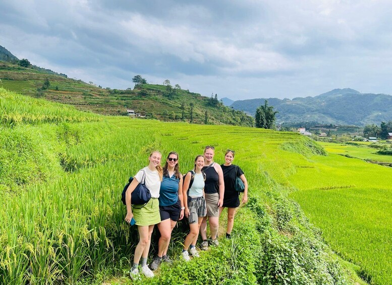 A group of people standing in a lush green rice field with terraced hills in the background. 2