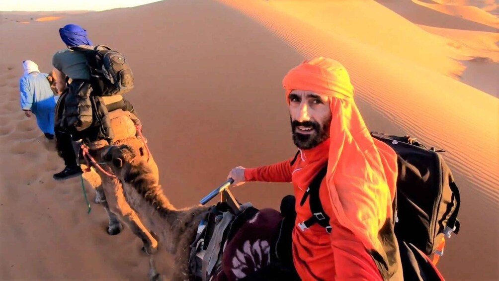 A person riding a camel in a desert with sand dunes. 5