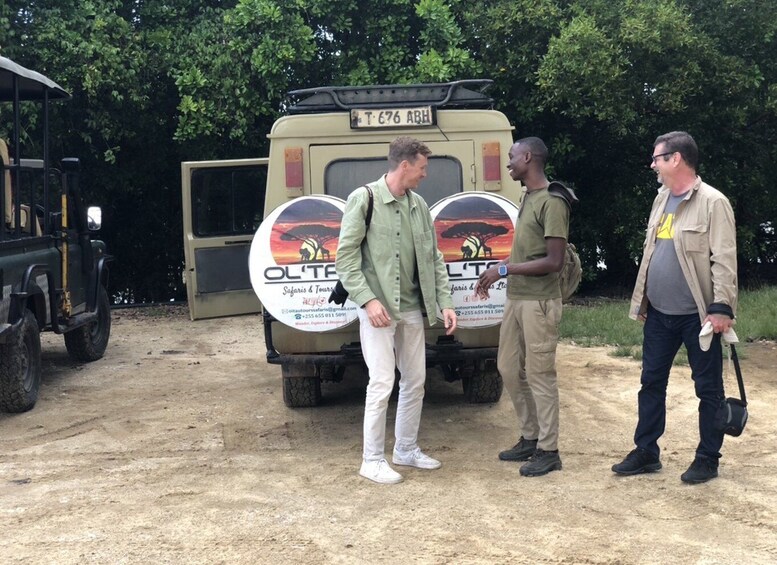 Three people standing in front of a safari vehicle with a sign that reads "OL' T'GO". 4