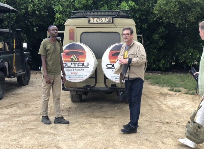 Two men standing in front of a safari vehicle with 'OL'TAU Safaris & Tours Ltd' branding. 3