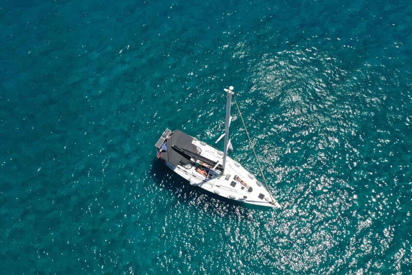 An aerial view of a sailboat on clear turquoise water. 1