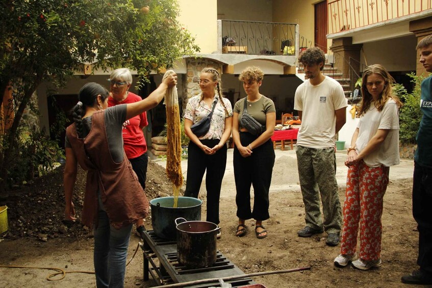 A group of people outdoors, some holding long strands of material, possibly for a craft or activity. 1