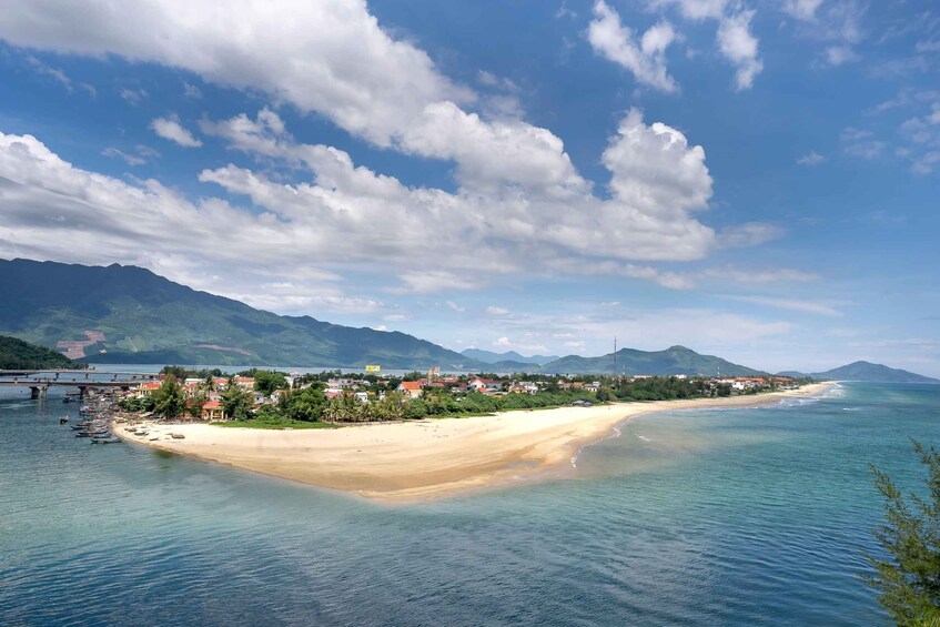 A coastal town with a sandy beach, clear blue waters, and mountains in the background. 5
