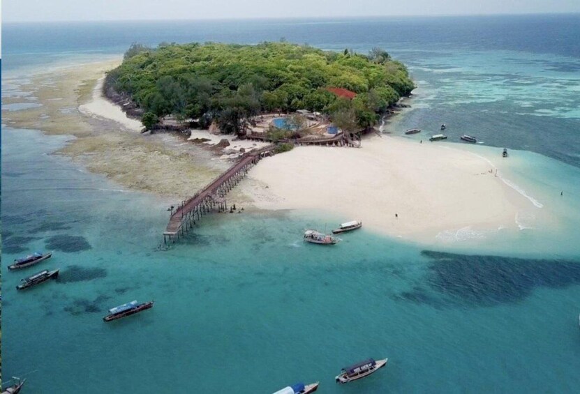 An island with a sandy beach, a pier, and several boats. 3