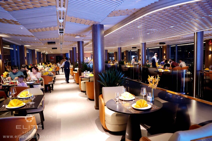 A modern restaurant interior with round tables, yellow napkins, and diners. 3