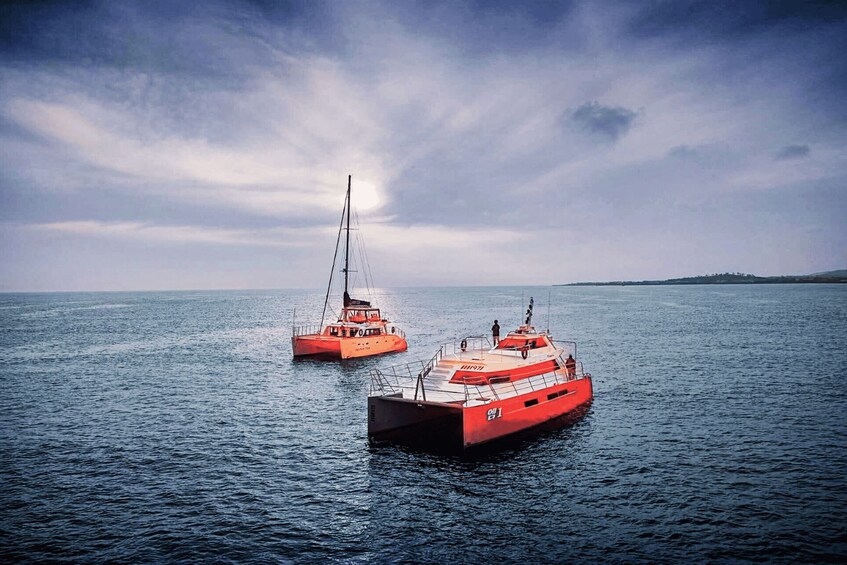 Two red boats on calm water with a cloudy sky. 4