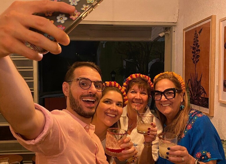 Three people taking a selfie, holding drinks, and wearing floral headbands. 3