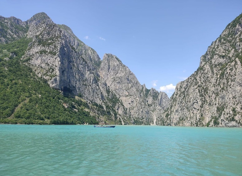 A boat on turquoise water with rocky cliffs in the background. 1