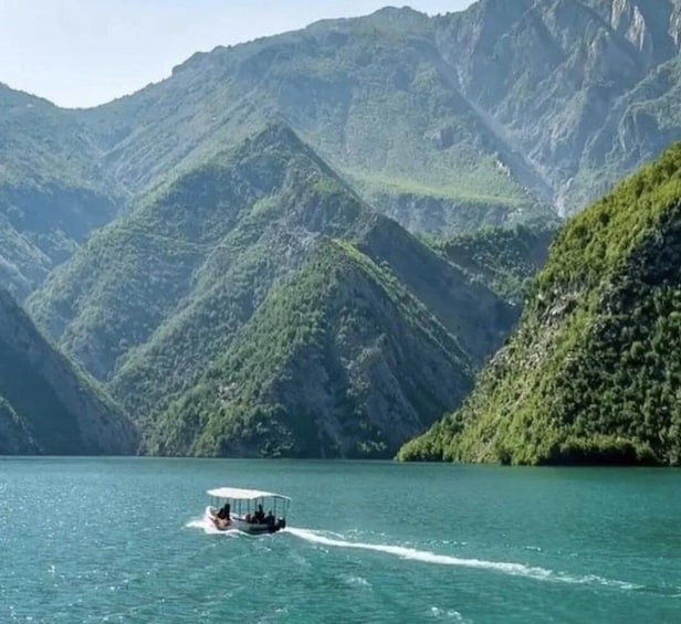 A boat on a calm lake surrounded by lush green mountains. 3