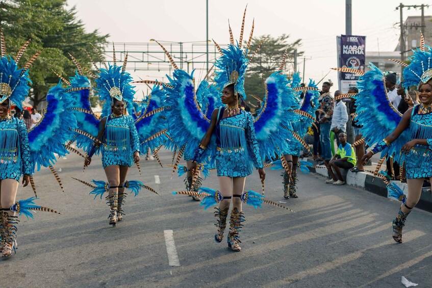 A parade with performers in blue costumes and feathered headdresses. 2