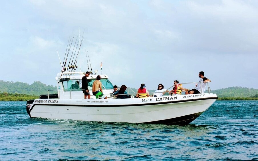 A boat named M.F.V CAIMAN on the water with passengers. 3