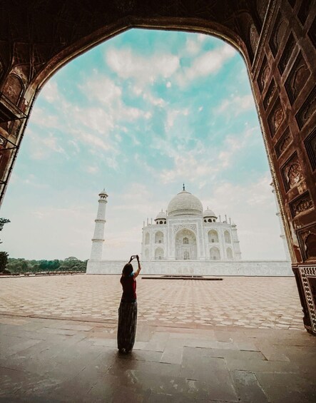 A person taking a photo of the Taj Mahal through an archway. 5
