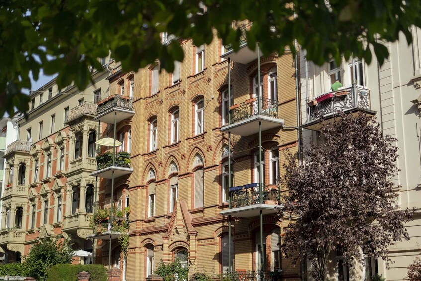 A row of historic buildings with ornate balconies and a tree with purple flowers. 3