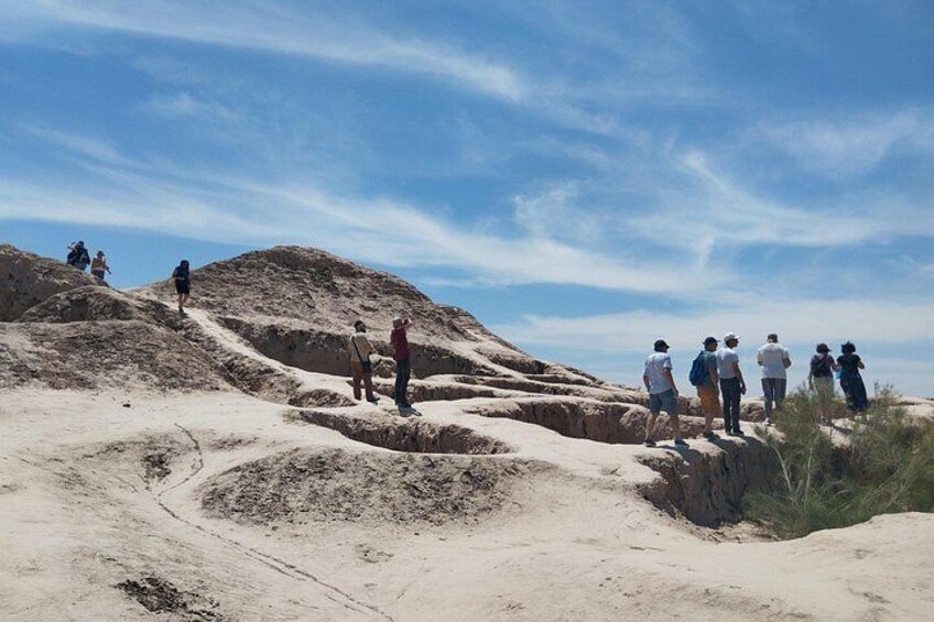 A group of people hiking on a sandy trail with a clear sky above. 3