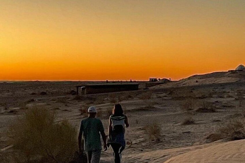 Two people walking on a desert path during sunset. 4