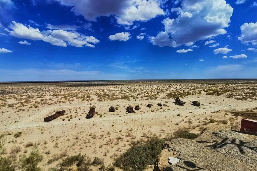 A desert landscape with scattered rocks and sparse vegetation under a clear blue sky. 2