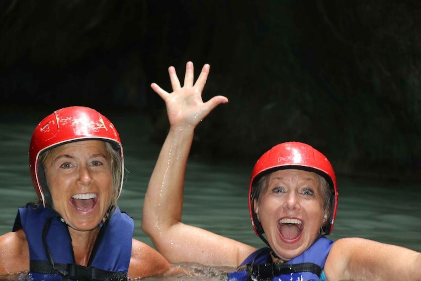 Two people wearing helmets and life jackets in a body of water. 5