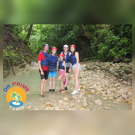 A group of people standing in a shallow river surrounded by greenery. 2