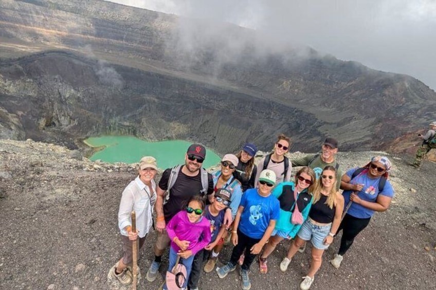 Un grupo de personas sobre un terreno rocoso, con un lago verde al fondo. 1