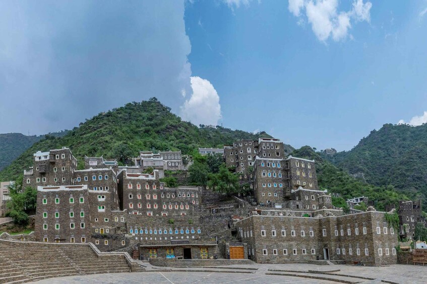 A historic walled town with traditional architecture, steeply terraced buildings, and a mountainous backdrop. 3