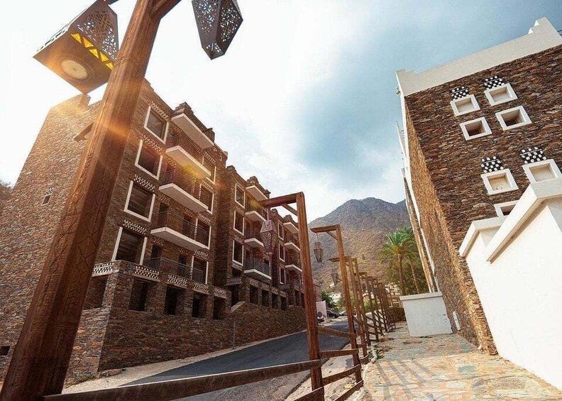 A narrow street with traditional architecture, a wooden gate, and mountains in the background. 2